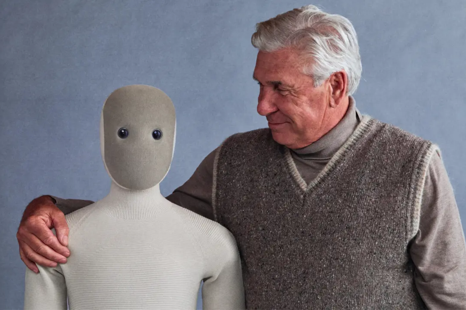 De stoffen Neo-robot met creepy ogen, naast een oude man die hem omhelst.